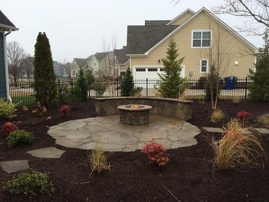 A natural stone patio with a fire pit creates a beautiful outdoor living area.