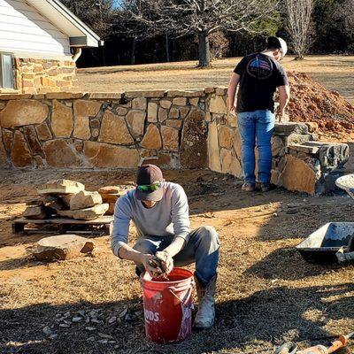 Our crew hard at work placing natural stones in the wall