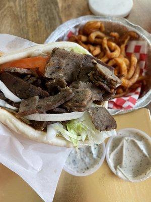 Beef gyro with sauces on the side and curly fries