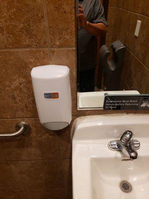 Empty soap dispenser in restroom.