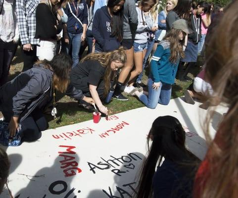 New students sign their names on a campus sidewalk.