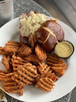 The Neuban Sandwich, corned beef and sauerkraut on a pretzel bun with a side of sweet potato fries