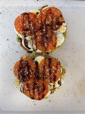 Avocado toast on an everything bagel w/ egg, tomato and balsamic drizzle