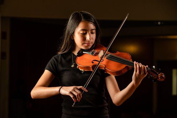 A Merit private violin lesson student poses with her instrument.