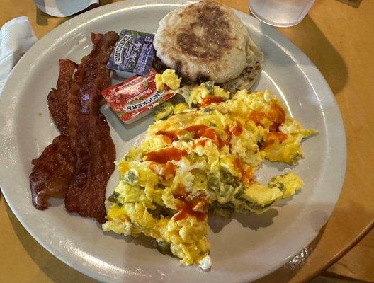 Original platter with bacon and English muffin and three scrambled eggs with cheese and jalapeños and a dash of hot sauce.