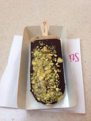 Coffee gelato stick dipped in dark chocolate with pistachio