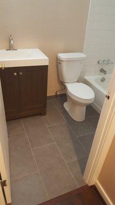 Bath remodel complete with new tiles, paint, toilet, and vanity installed.