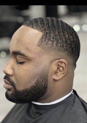 Low skin fade that's faded into the beard.  Top was trimmed with the grain to make the waves extra wavy.