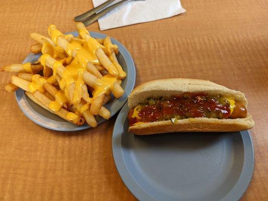 Hot dog with ketchup, mustard and relish. Fries with cheese.