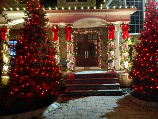 Welcome Home! LED accent trees light entry, lit garland w/ lit bows on columns, Signature Garland-fr. door, C-9 LED  gutters, gables/roof