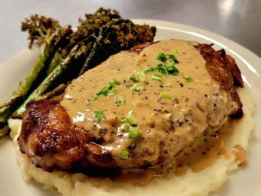 Weekly Special: Pan seared NY strip steak on a bed of garlic mash, topped with bourbon peppercorn sauce, and a side of fried broccolini