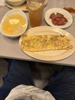 4 egg omelette with mushrooms onions green peppers and cheese , cheese grits with butter , sweet tea. And 2 slices of fried beef bologna.