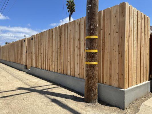 Cedar Board-on Board fence with steel posts atop a new concrete short wall.