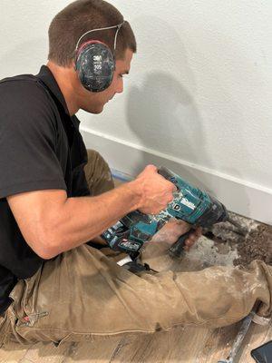 Brock using a Makita battery operated chipping hammer to expose a leak in a slab causing a high water bill.