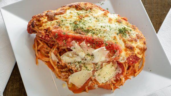 Chicken Parmigiana - Breaded chicken cutlet, smokey tomato sauce, parmesan and mozzarella over spaghetti.