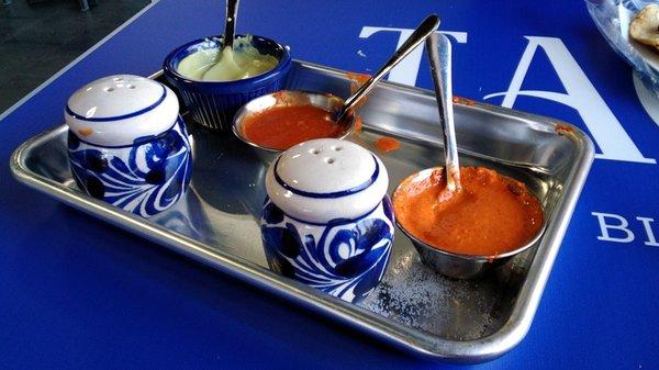 Tray of 3 different salsas, and salt shakers.