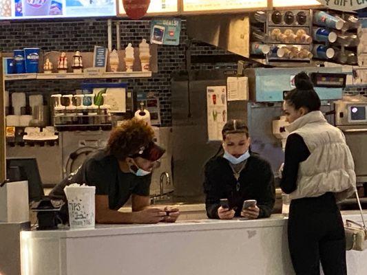 Employees laying on the counter having inappropriate conversation with their friend.