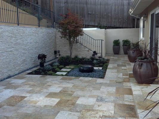 Travertine patio, small garden area with water feature.  Stone veneer on retaining wall