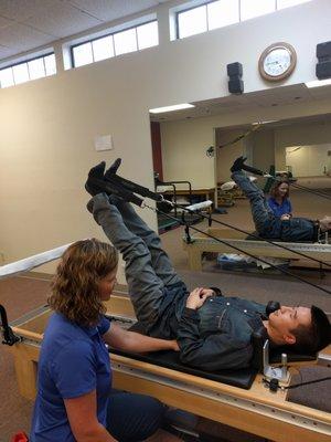 Heather Rose, MPT teaching core exercises on a Pilates reformer