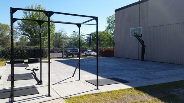 Outdoor workout area with official high school half court and 6 station pull up rig.