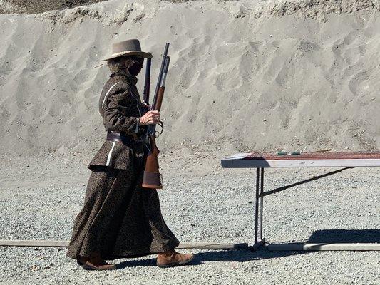 A Cowboy Action Shooter (CAS) carrying her firearms to table.