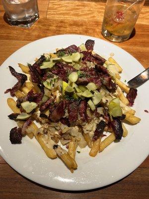 Pastrami Poutine: House smoked pastrami, whole grain mustard beer cheese, sauerkraut, and pickles over crispy french fries.