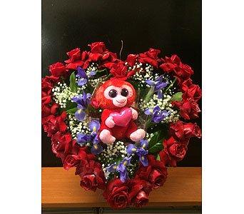 open heart made of red roses with irises and stuffed monkey in the center