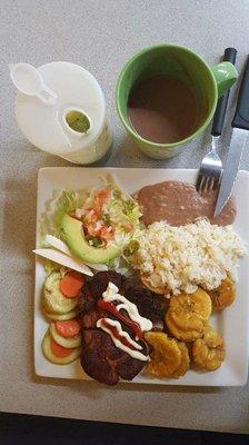 Lunch platter, pork chop, rice, beans, cucumber & tomato salad