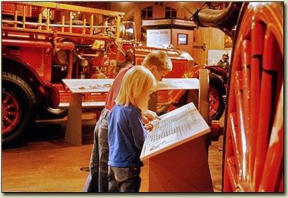 visitors to the Aurora Regional Fire Museum reading about a learning how a steam fire engine operates