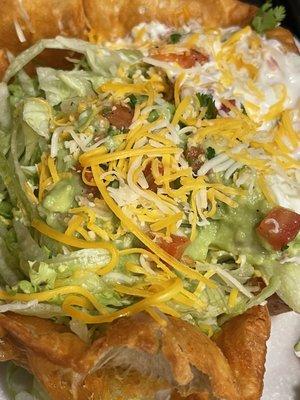 Close up haha of Tostada without meat. Beans, lettuce, cheese, guacamole, sour cream, etc.