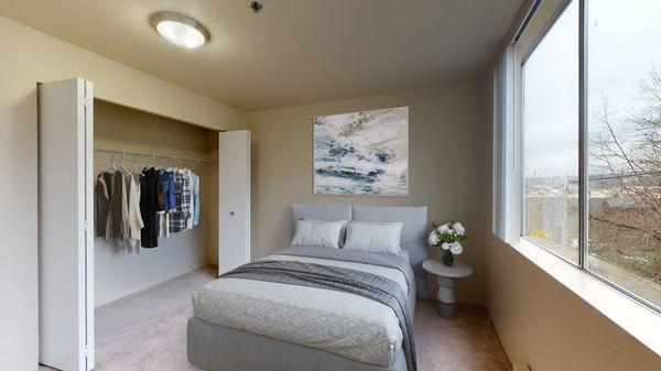 Bedroom with carpeted floors, a large window, and closet space.