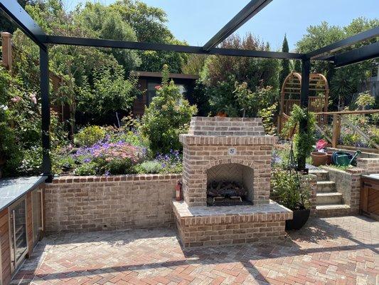 After:  brick patio with fireplace, cottage style garden