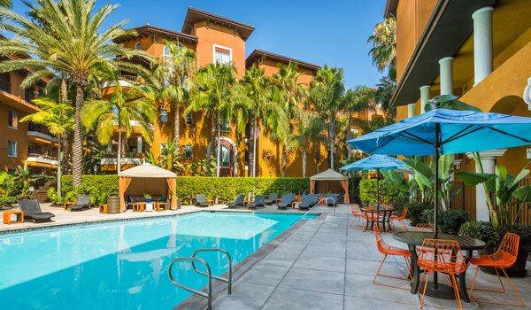 Resort-style pool with lounge chairs and covered tables