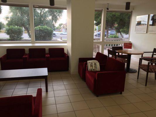 Red velvety chairs in the waiting area matches the chairs at the table next to it. Comfy.