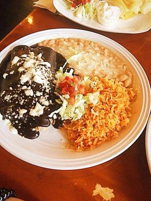 A Chocolate Chilata known as a "Enchilada De Mole".  With the Red Rice N' Cheesy Beans iceberg lettuce shreds and salsa garnish.