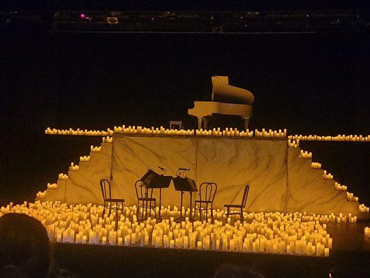 Stage full of candles for concert of holiday music.