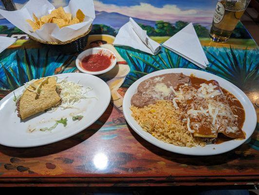 Combination plate of a taco, 2 enchiladas rice and beans. With chips and salsa and a beer in the background.  I highly recommend