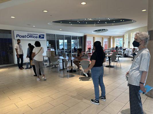 A line of customers waiting for the post office to open DURING THEIR BUSINESS HOURS, because it's closed.