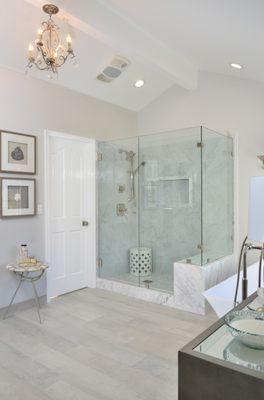 The new frameless shower enclosure showcases  new marble tile with a new niche, and bench seating, in this award-winning Danville bathroom