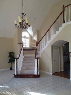 Fresh paint on walls, stair balusters, and trim with freshly varnished railing and bottom step.