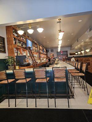 The large long bar with nice lighting and the booths on the right side. Many couples were seated at the bar.