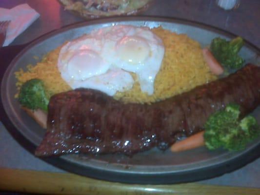 Churrasco with yellow rice and two eggs over easy