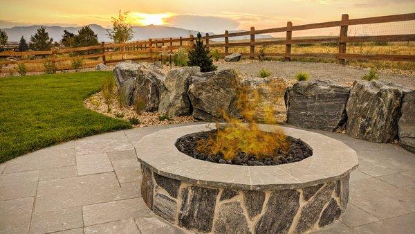 Candelas custom stone firepit with surrounding paver patio, landscape boulders, native plantings.