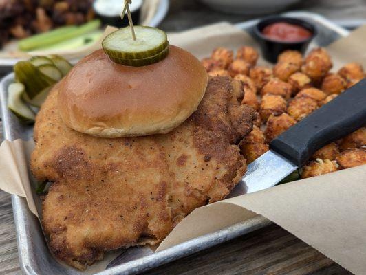 Crispy pork tenderloin sandwich with sweet potato tots.