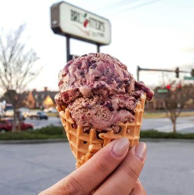 A scoop of chocolate Raspberry truffle in a waffle cone.