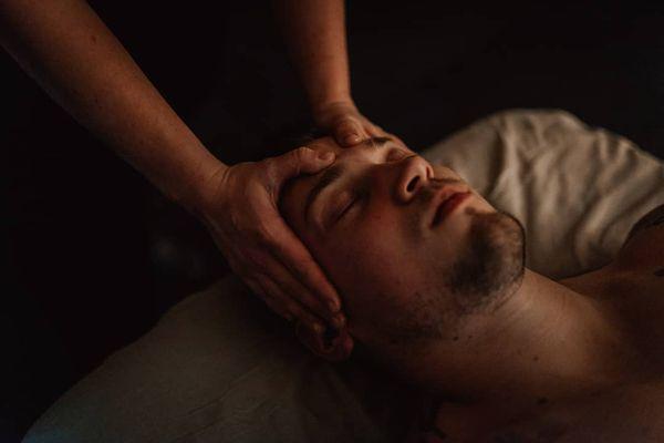 Lauren applying massage therapy techniques to the frontalis, temporalis, and masseter muscle groups on both sides of the forehead.