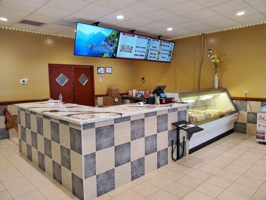 Front counter with a deli case of desserts and sides.