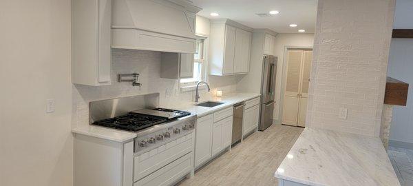 Custom galley kitchen remodel with custom cabinets, pot filler, commercial chef appliances, and exotic quartzite countertops.