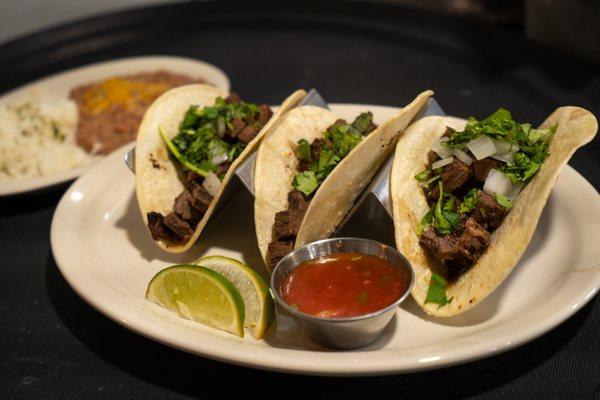 Beef Street Tacos. Soft corn tortillas with cilantro, onions, fresh salsa and limes. Served with refried beans and rice.