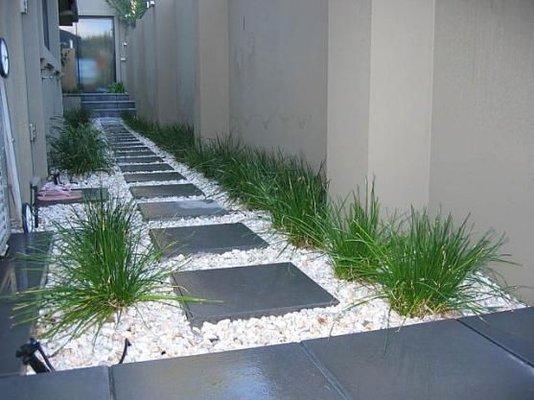 Side of the house landscape design with Patio pavers and white rocks. Plant are also part of the design